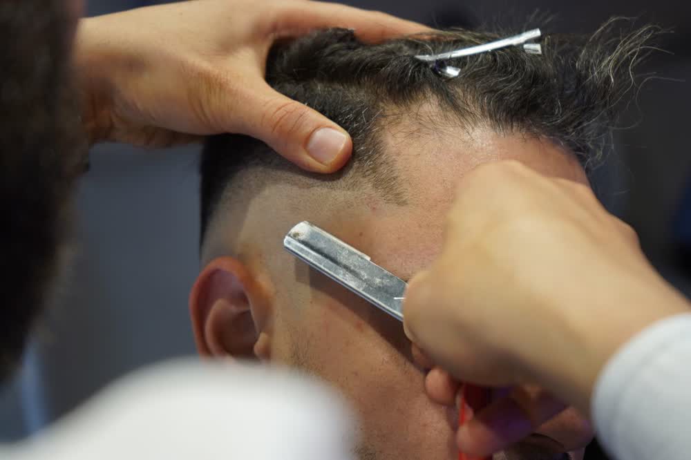 Barber werkt een fade bij met een scheermes